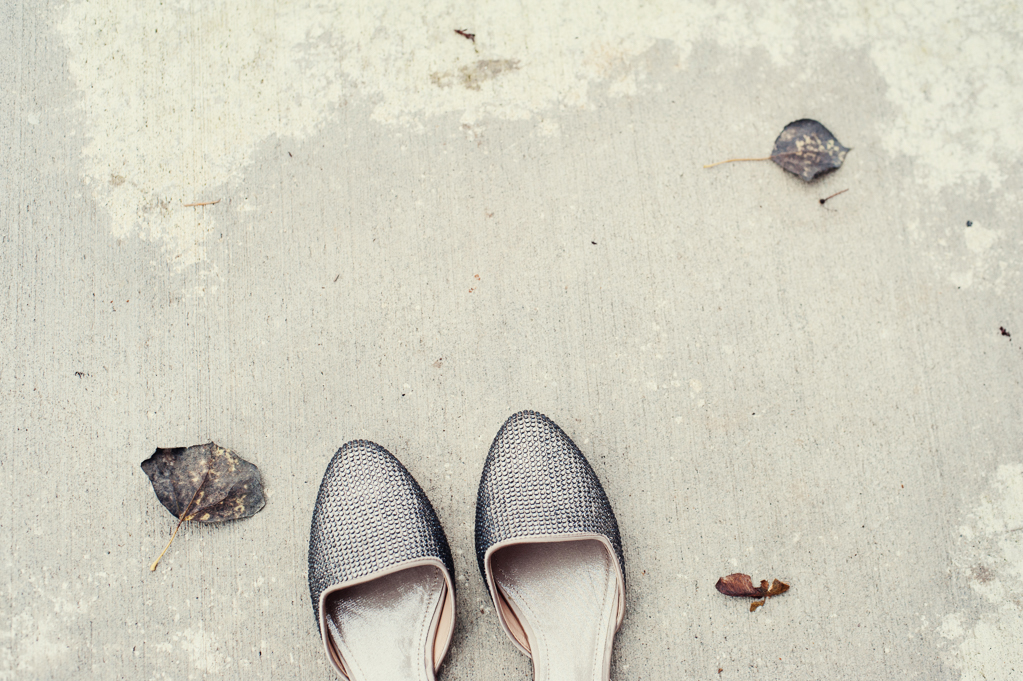 silver wedding shoes on the sidewalk