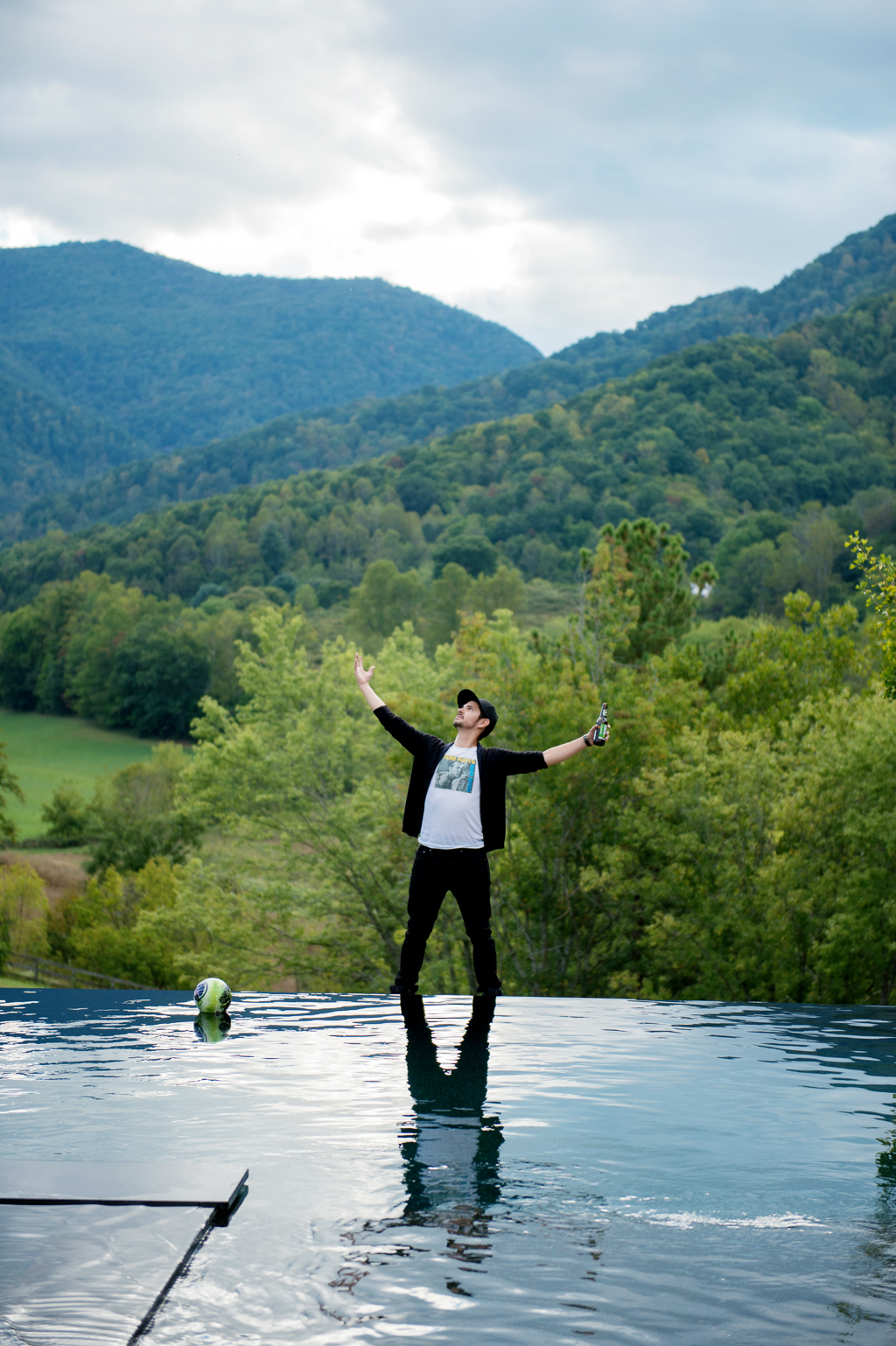 a man stands at the end of an infinity pool overlooking the blue ridge mountains