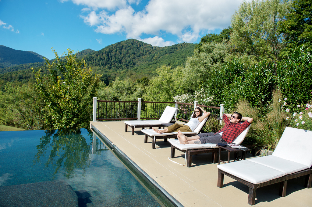 a couple lounge next to an infinity pool overlooking the blue ridge mountains