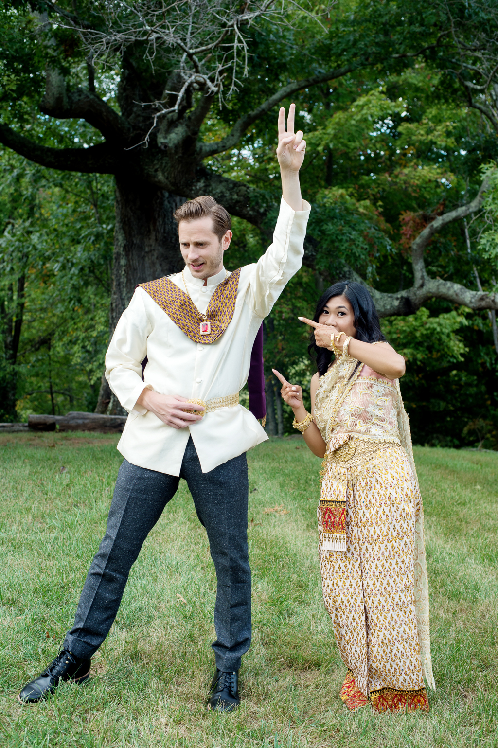 a couple wearing traditional gold cambodian wedding attire make a silly pose