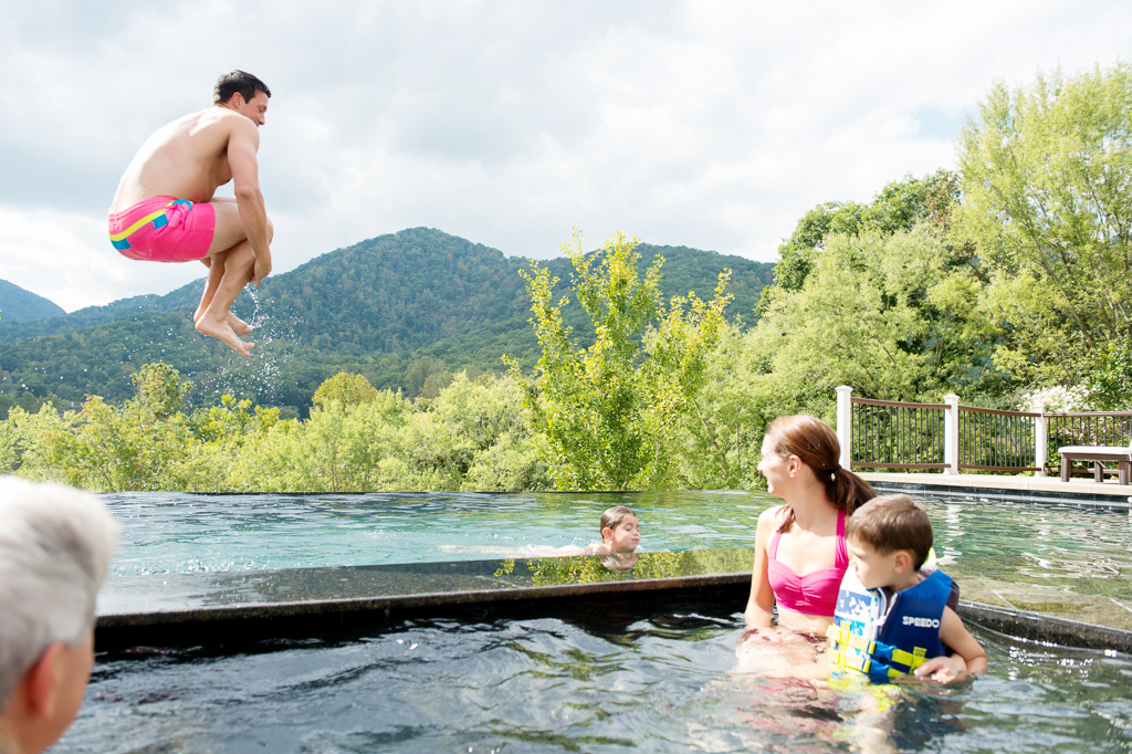 a man does a cannonball into an infinity pool overlooking blue ridge mountains