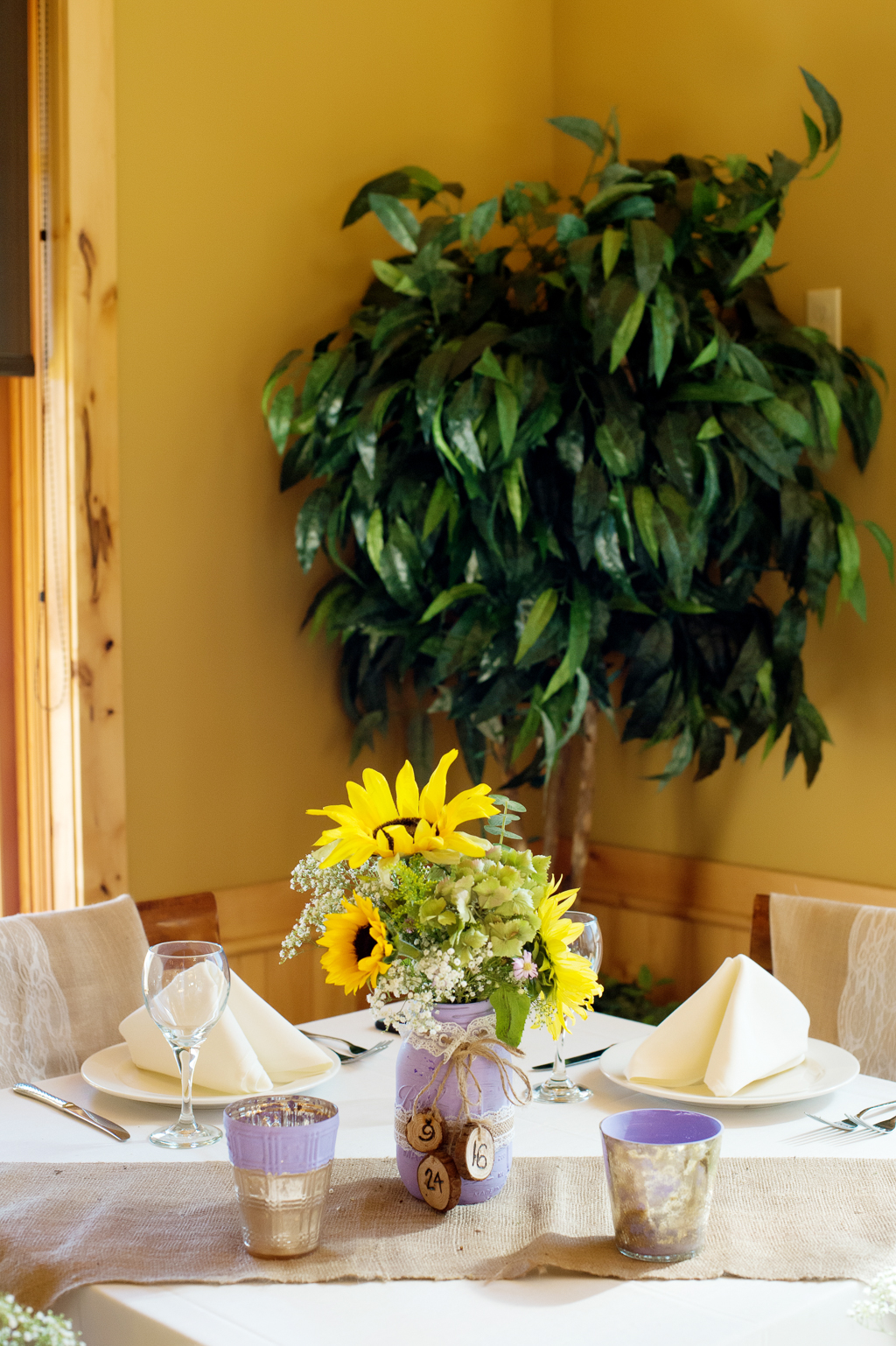 sunflowers and green hydrangeas in burlap covered and purple painted mason jars
