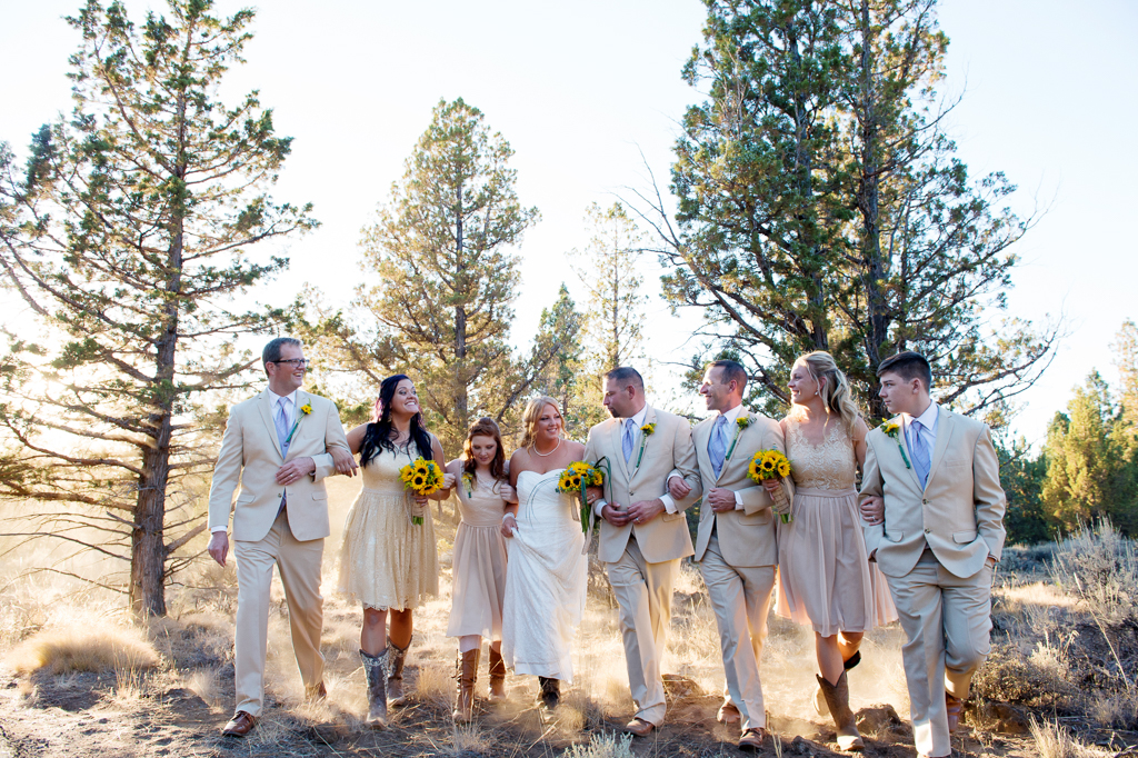 a wedding party in light tan attire walk arm in arm
