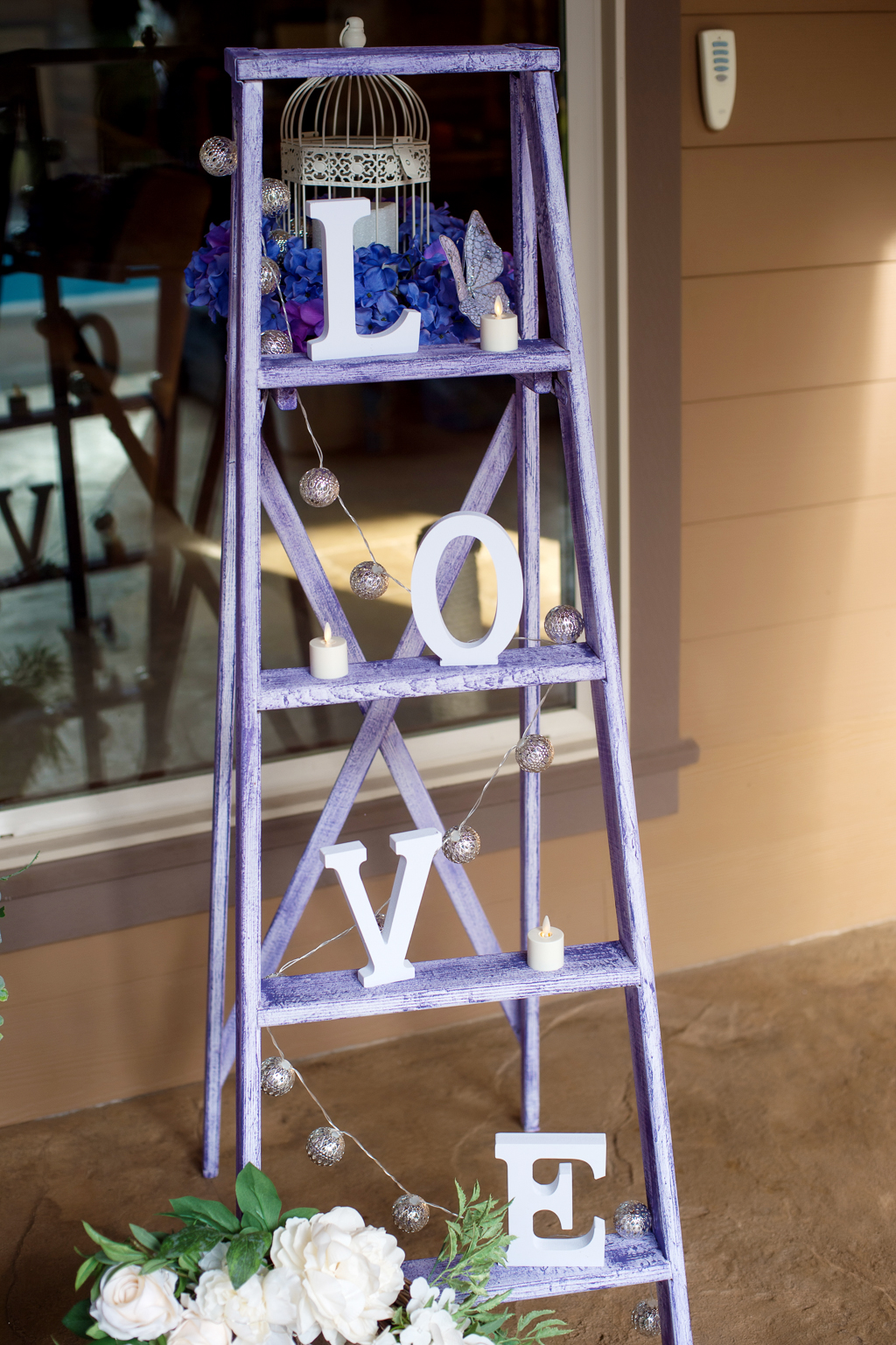 a purple wooden ladder holds wedding decoration and letters that spell out love