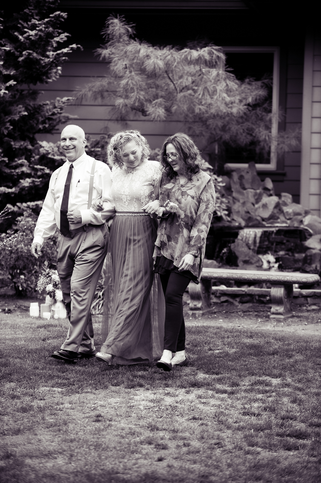 a bride holds back tears as her mom and dad walk her down the aisle