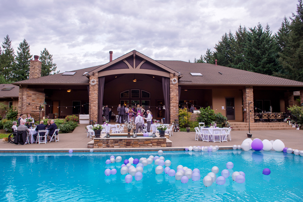 purple gray and white balloons fill a backyard swimming pool for a wedding reception
