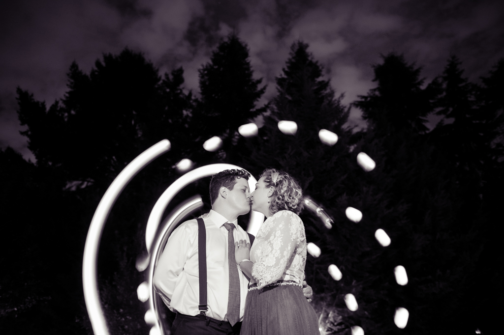 a bride and groom kiss together surrounded by trails of light at night