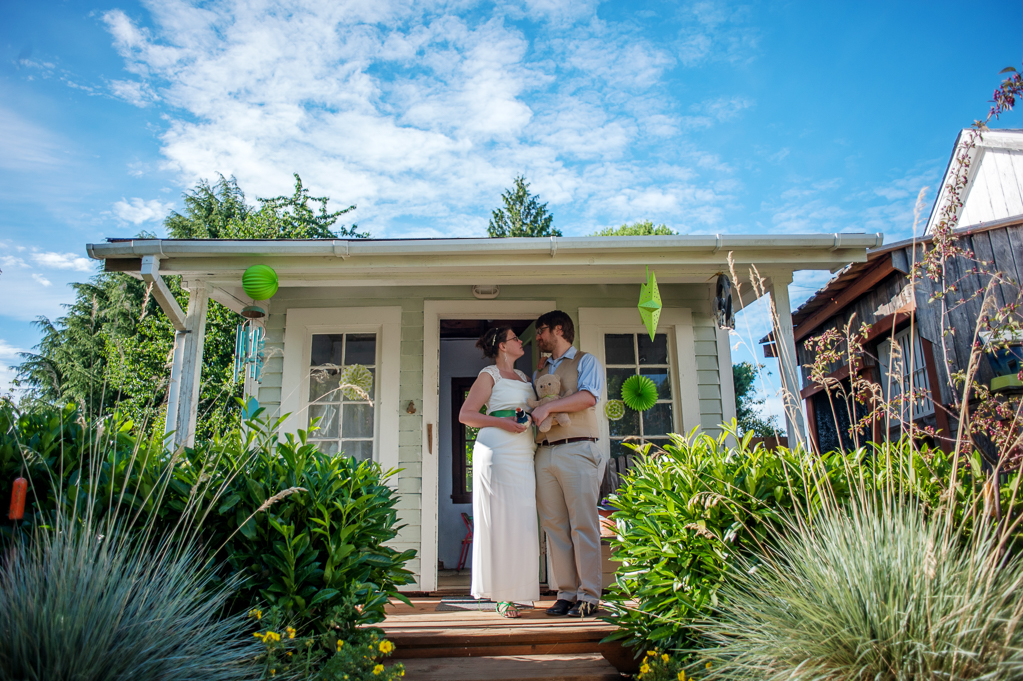bride and groom stand on the front porch of a garden shed where they got married