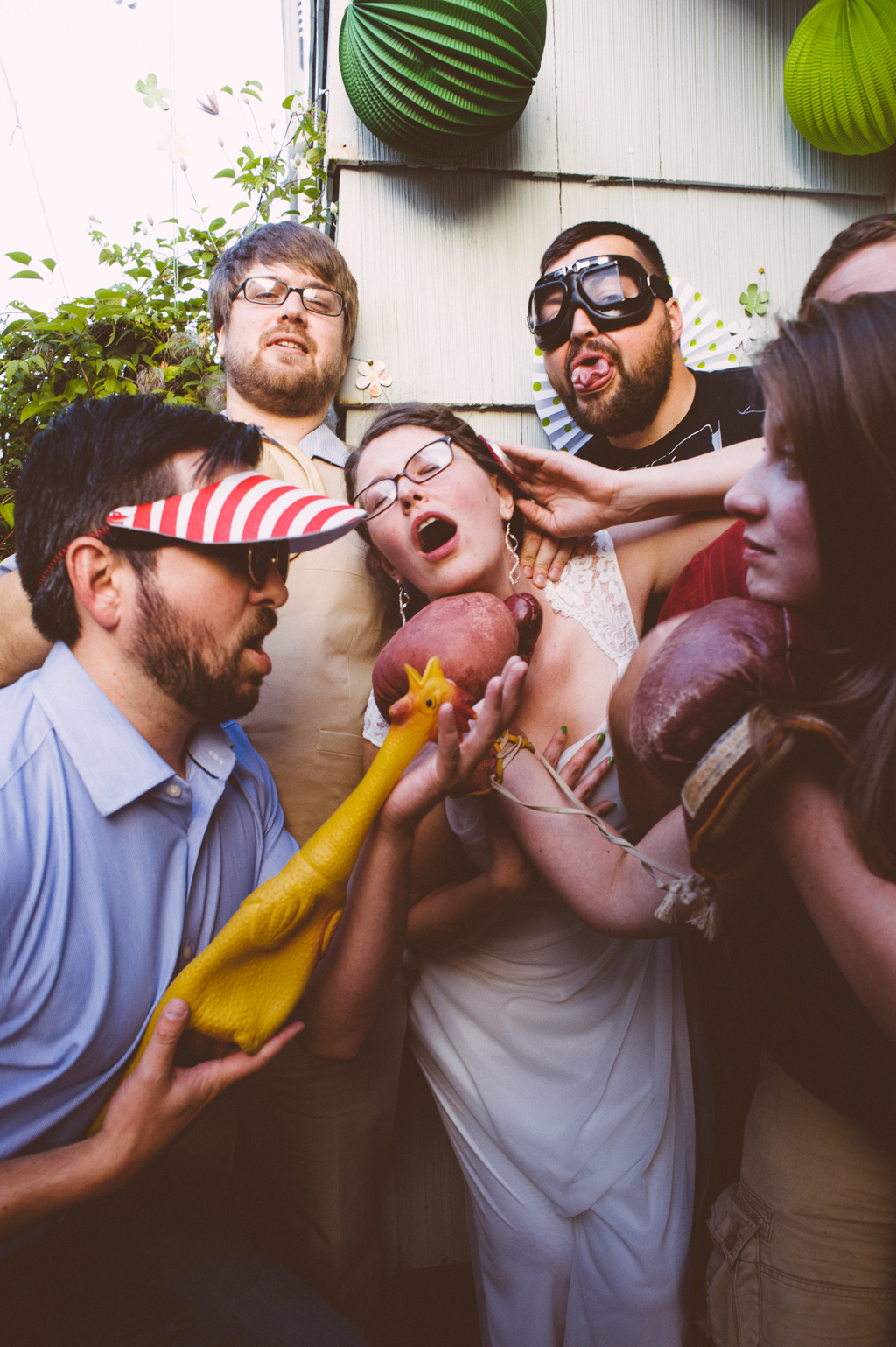 wedding guests get silly with a rubber chicken in a photo booth with the bride