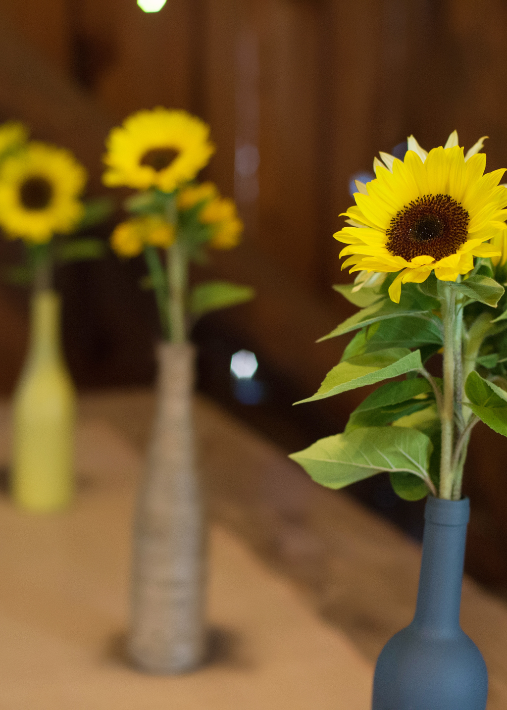 sunflowers in painted wine bottles line the table at a wedding