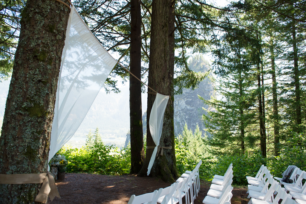 two sheer curtains hanging between trees create the ceremony backdrop with beacon rock in the background