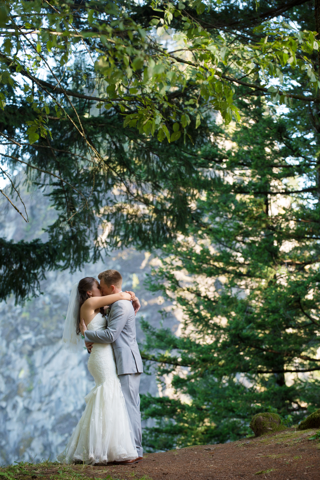 a bride and groom kiss in front of beacon rock