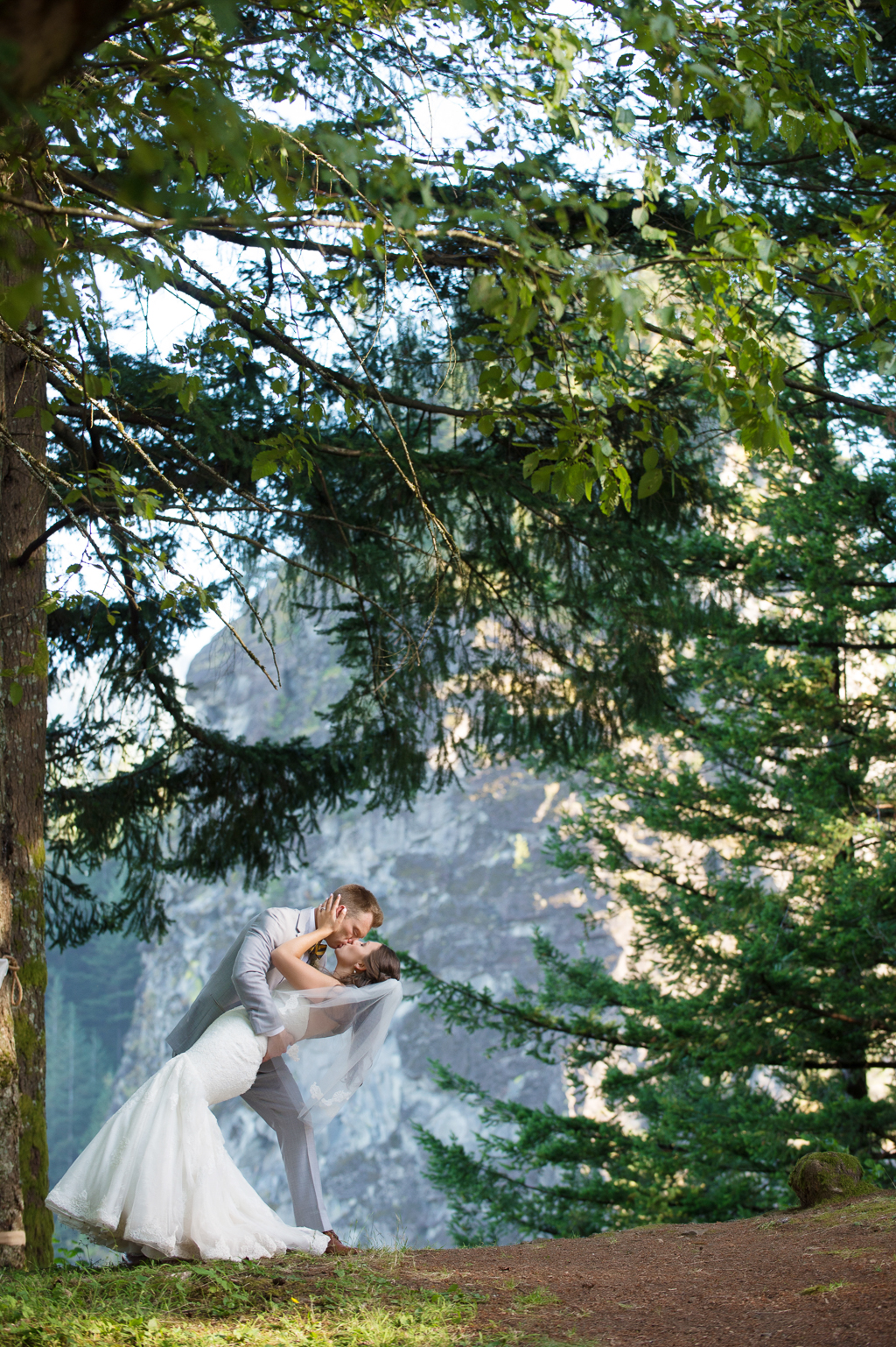 a bride and groom kiss with beacon rock in the background
