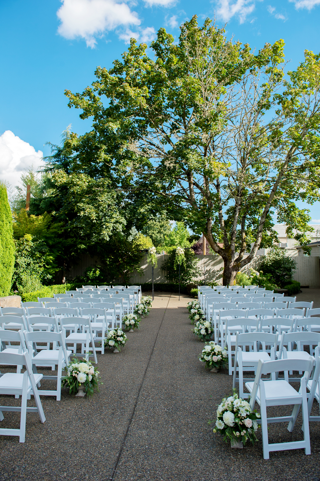 ivory and green bouquets line the ceremony aisle leading to a giant tree