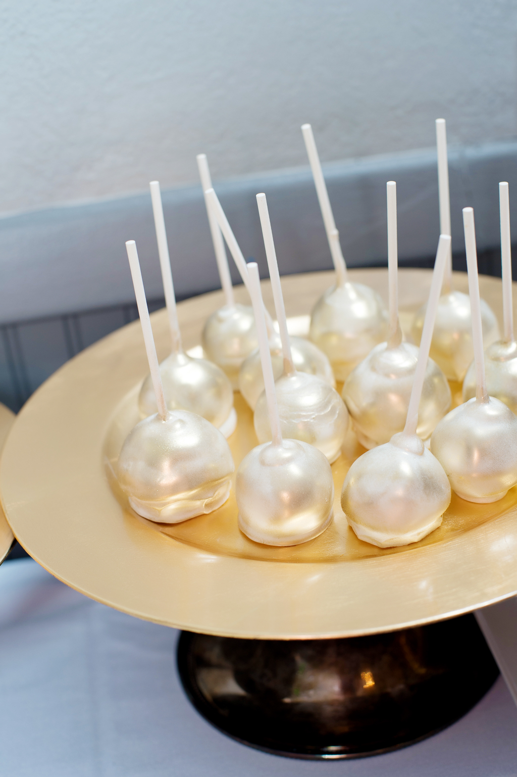 gold dusted cake pops sit on a gold tray