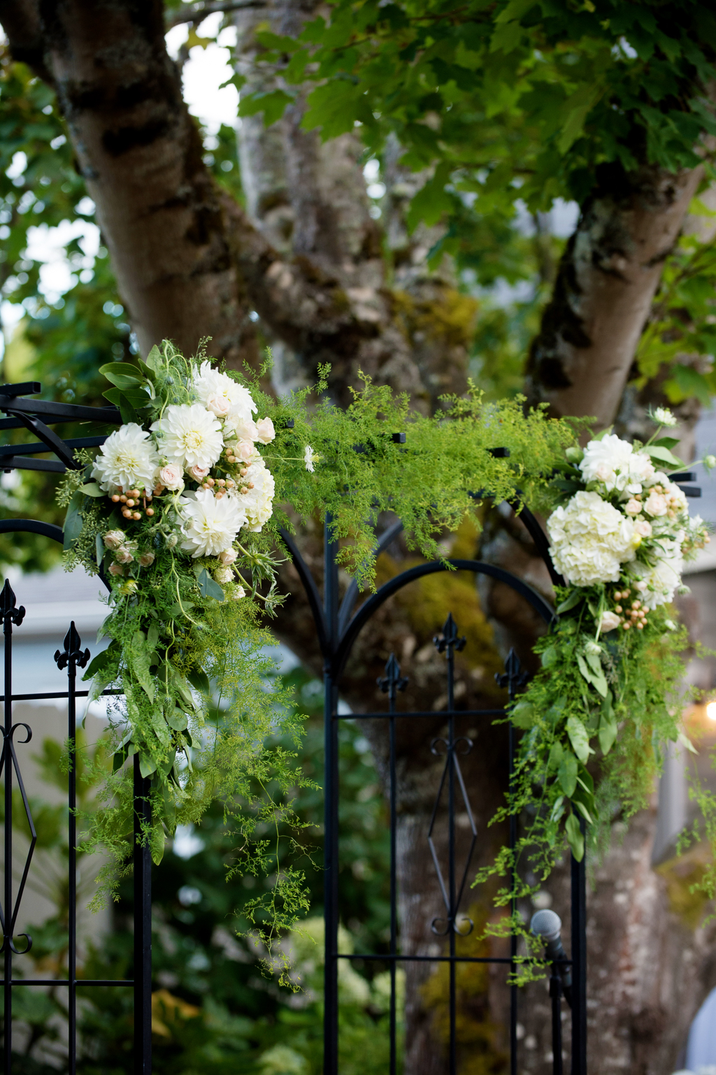 a wrought iron wedding arbor covered in green and ivory