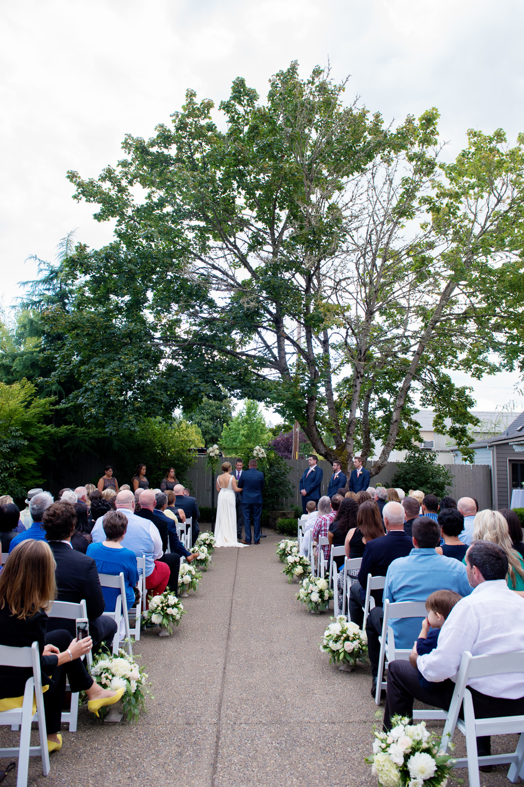 a wedding ceremony under a giant tree in the courtyard behind bella via
