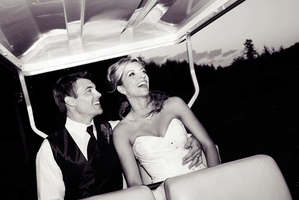 bride and groom laugh as they ride a golf cart