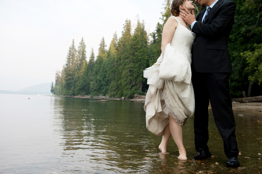 a bride and groom stand in the lake