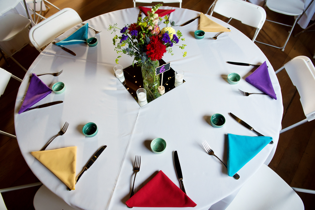 traditional mezcal cups and colorful napkins on the table for wedding reception with colorful wildflowers