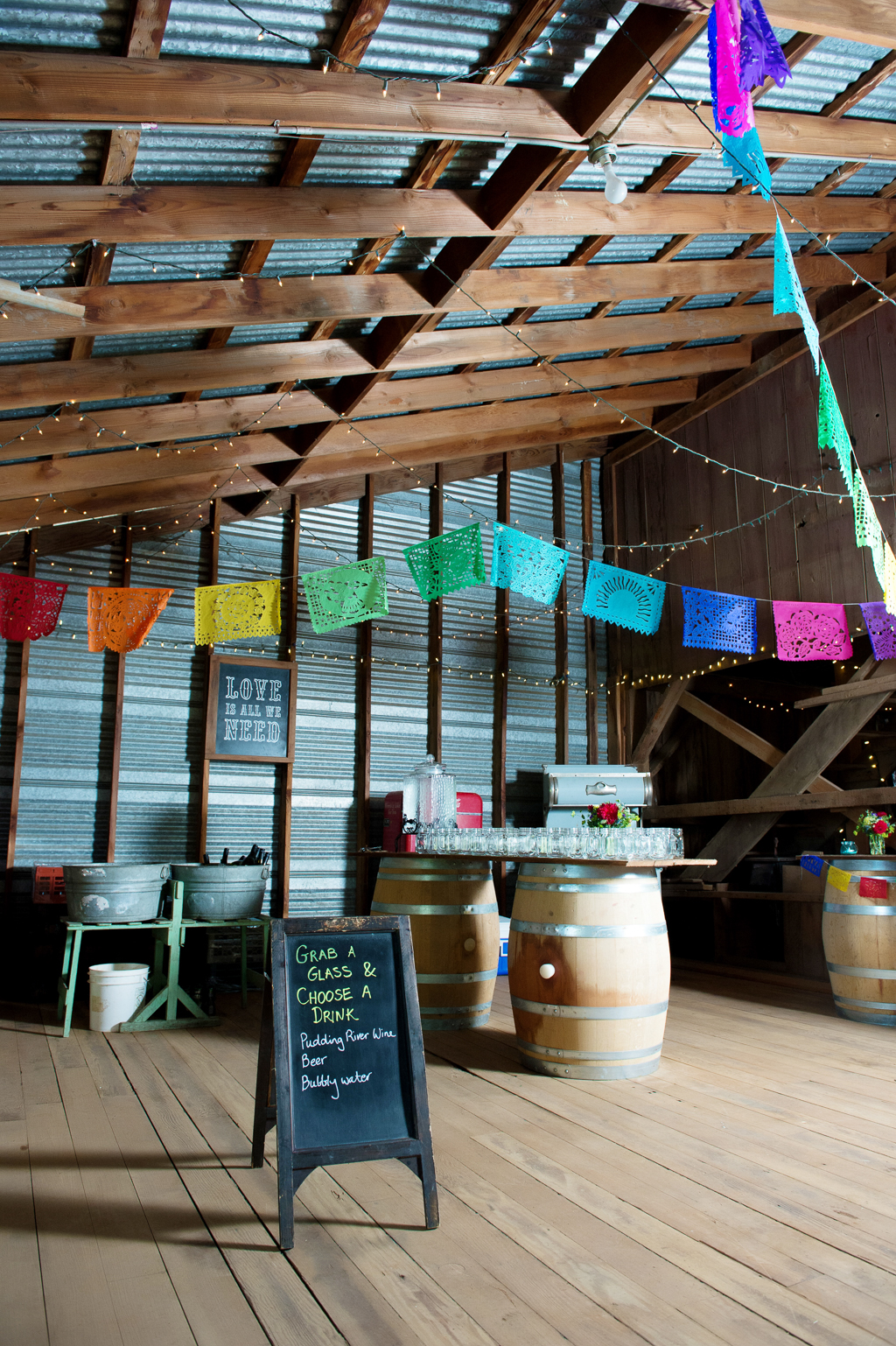 papel picado hang from rafters in a barn for wedding reception decor