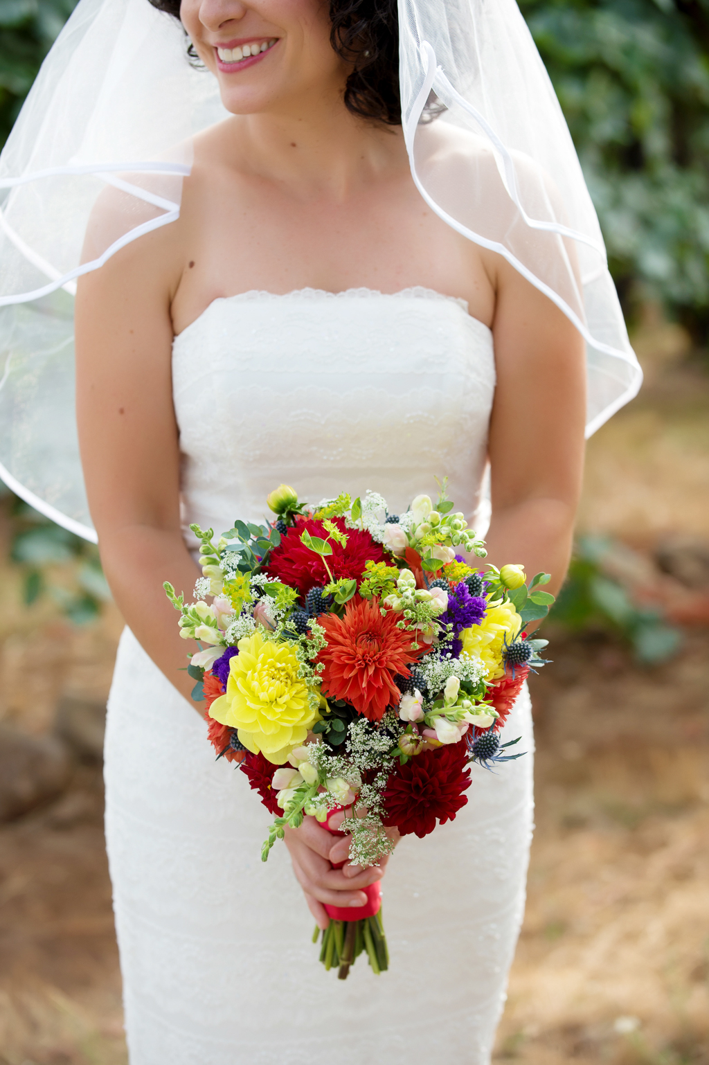 bride holds vibrant yellow red and purple bouquet