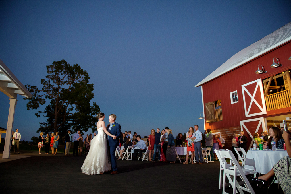 bride and groom have first dance in front of red barn