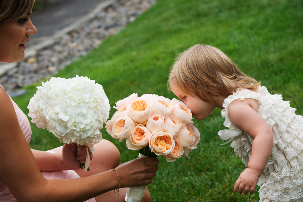 a little girl smells a bride's bouquet