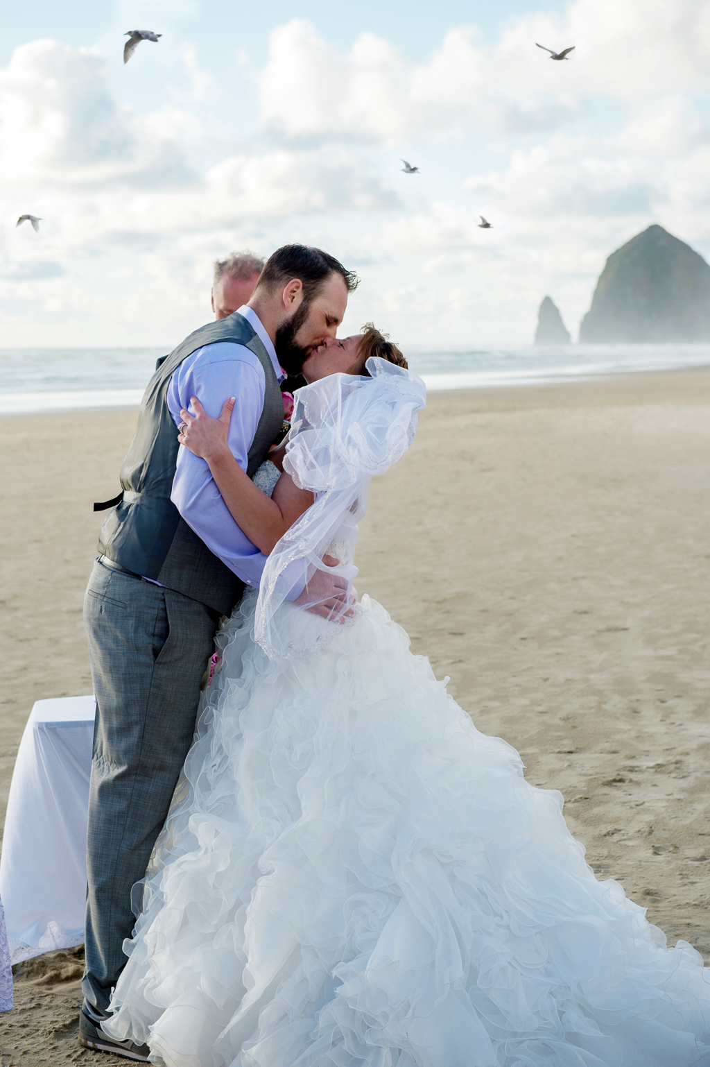 bride and groom get married on cannon beach as birds fly overhead