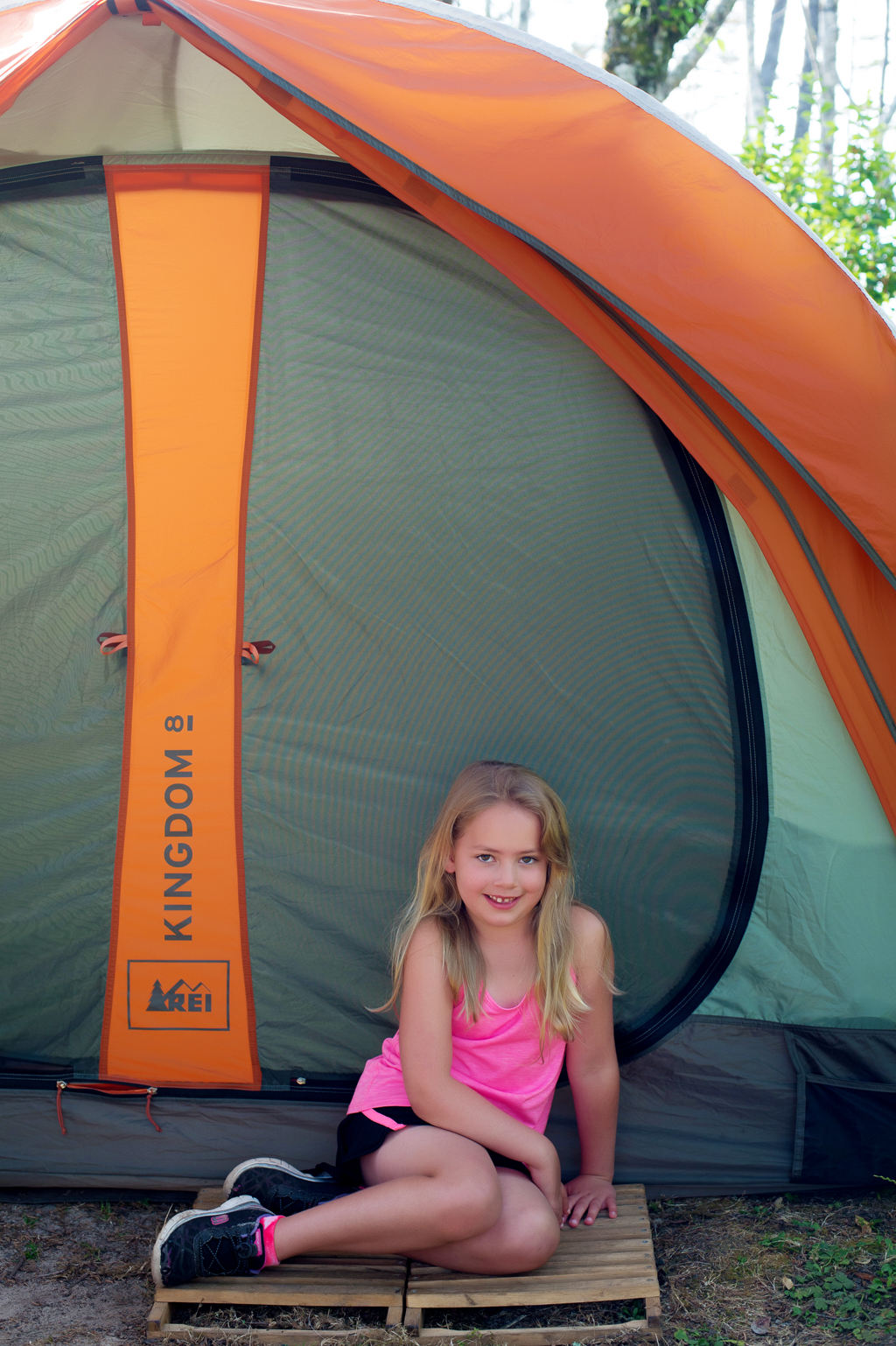 girl in front of orange and green tent