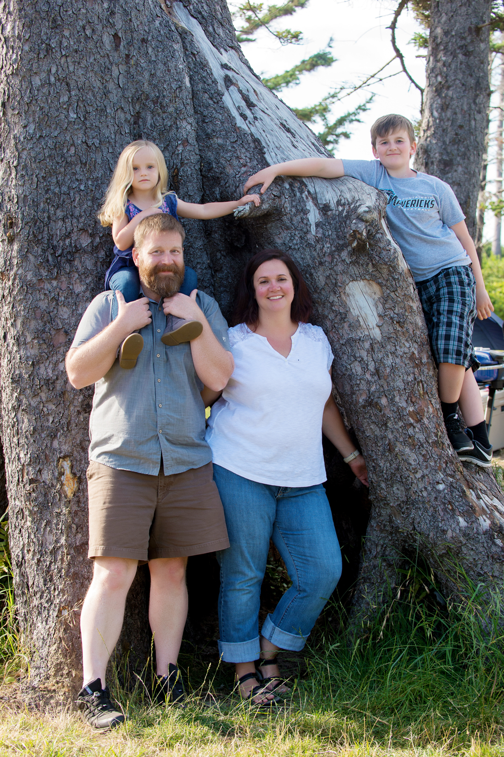 a family poses around a large tree at cape lookout state park