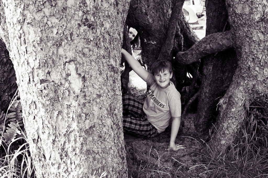 a young boy sits underneath tree roots