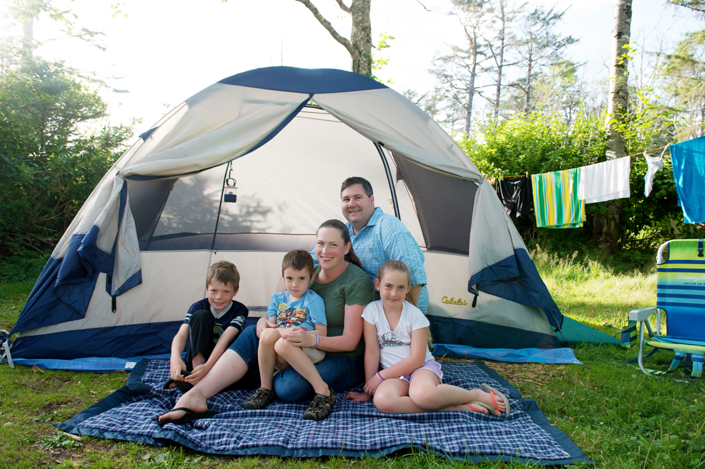 a family sits in front of their camping tent at cape lookout state park