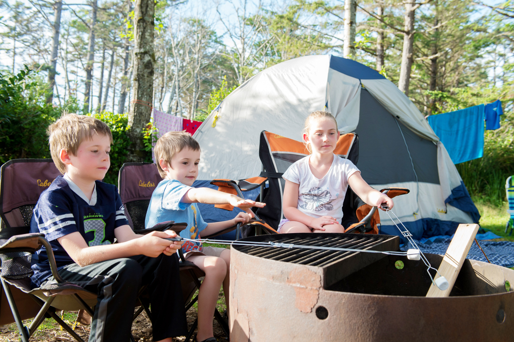 3 kids roast marshmallows at their campsite in cape lookout