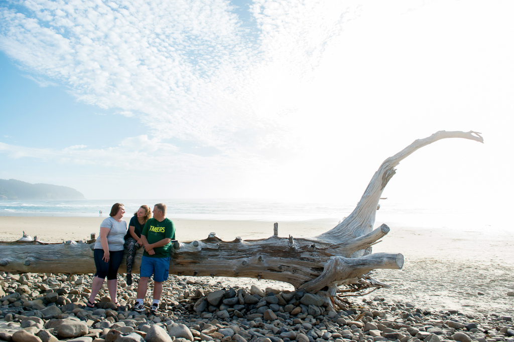 a family sits on a log on the beach