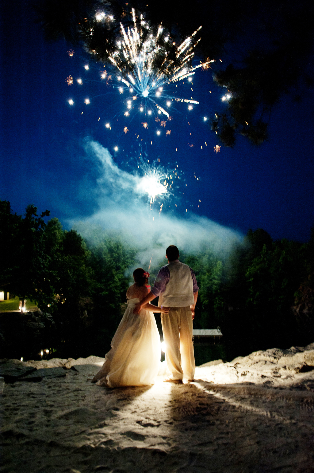 a bride and groom watch fireworks explode in the sky