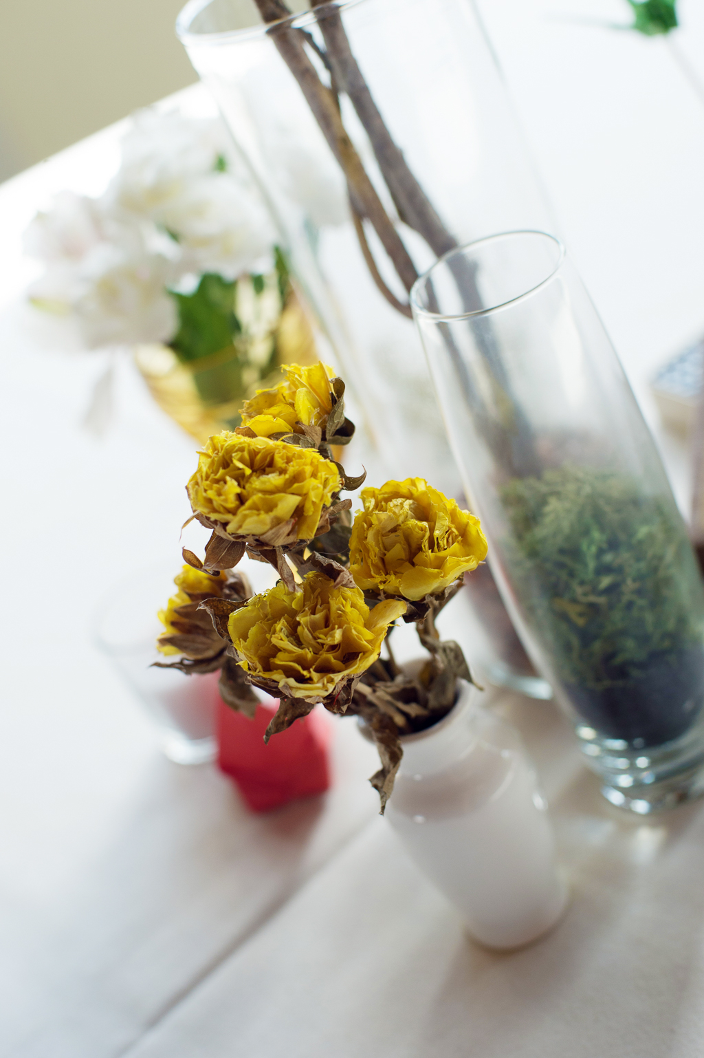 dried yellow flowers in a vase on a table at a wedding reception