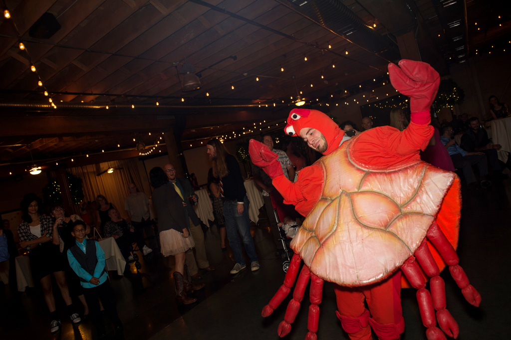 a wedding guest in a large red lobster costume surprises the bride and groom during the wedding reception