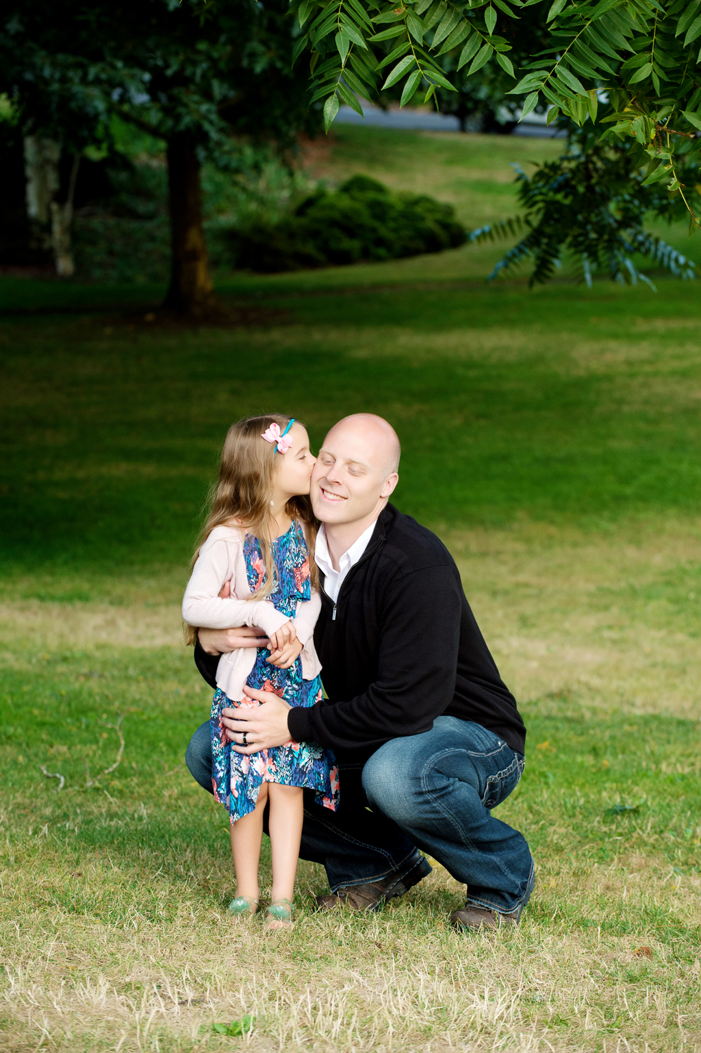 a little girl gives her dad a kiss on the cheek