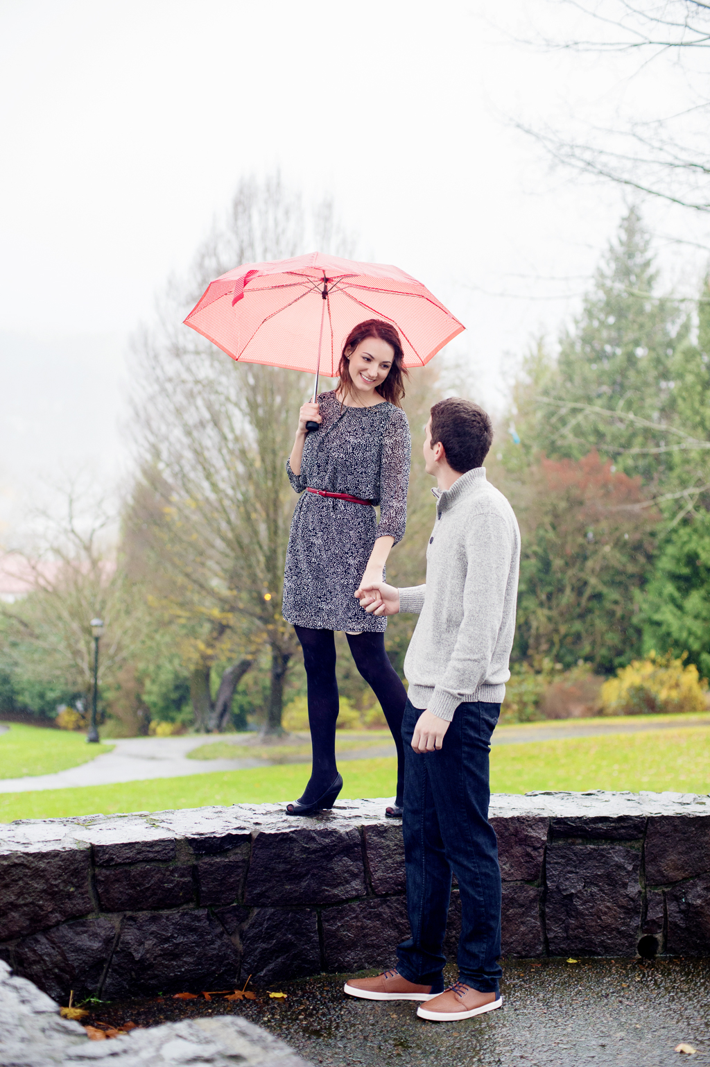 a girl walks with an orange umbrella while her boyfriend holds her hand