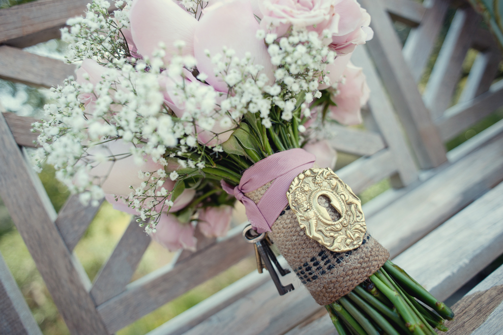 a pretty gold key lock and keys adorn a bouquet of pink roses and baby's breath