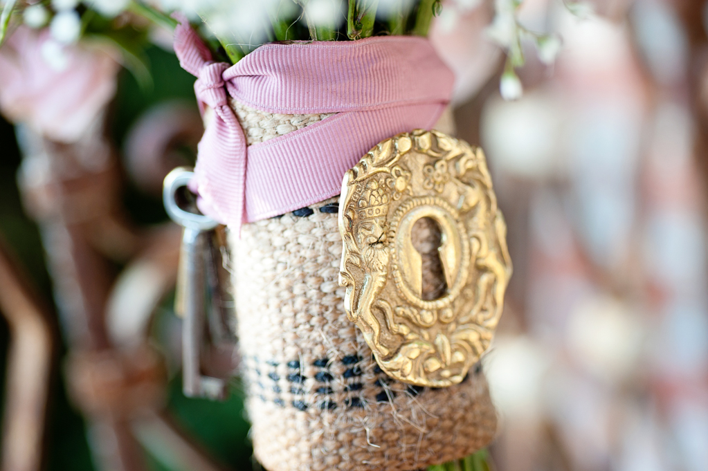 a pretty gold key lock and keys adorn a bouquet of pink roses and baby's breath