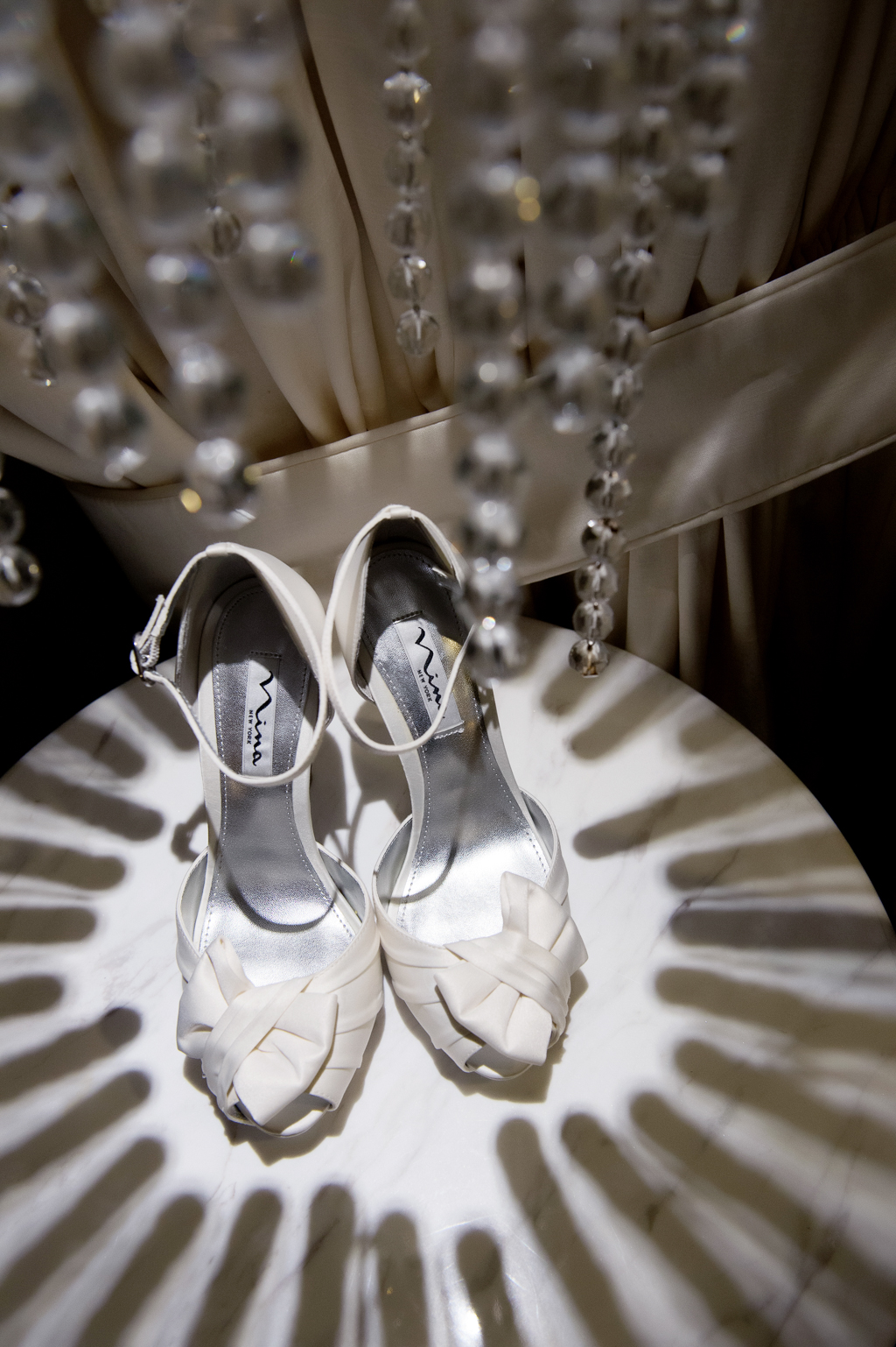 white shoes on a table covered in shadows from a crystal lamp