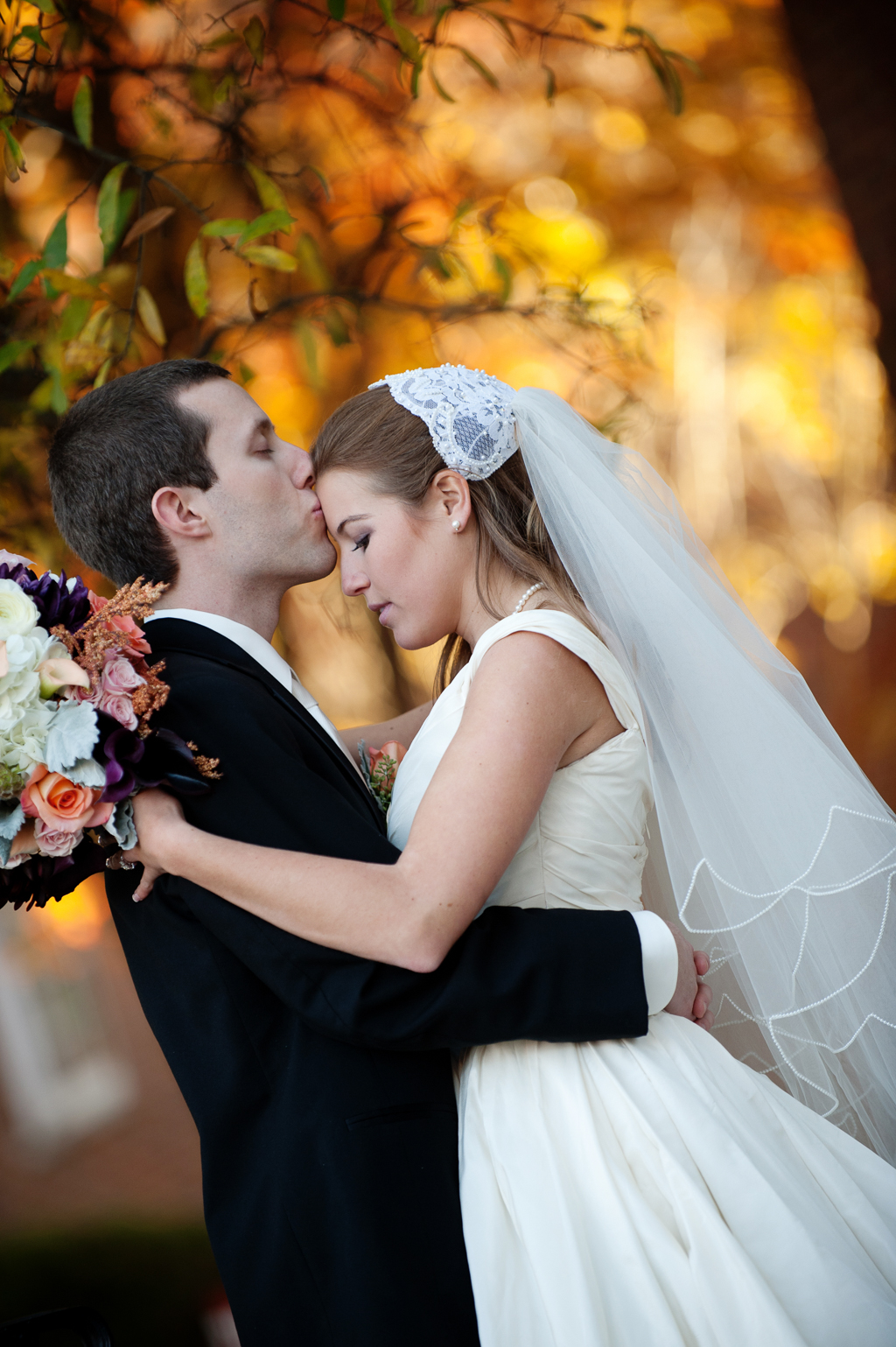 a bride and groom kiss in front of vibrant autumn colors