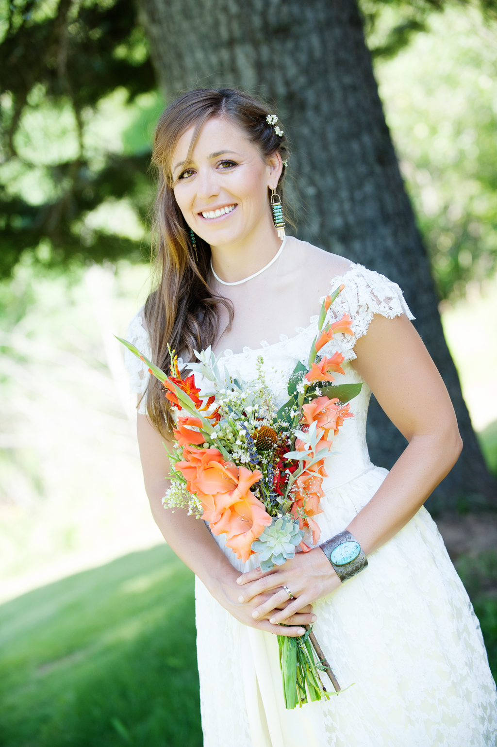 a bride holds a vibrant orange bouquet wearing a turquoise bracelet