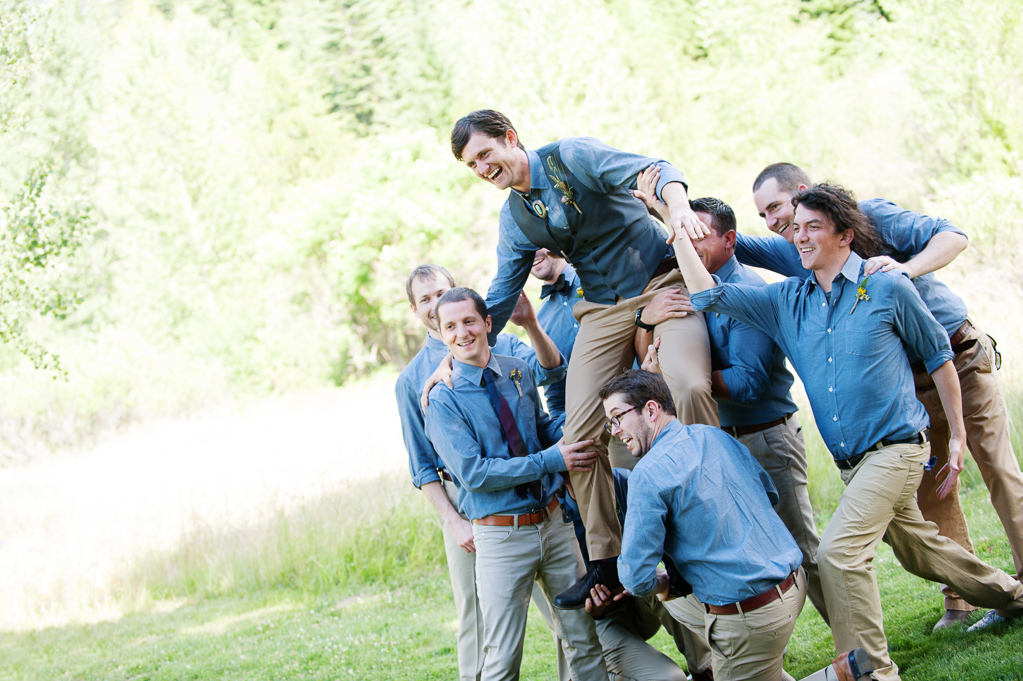groomsmen lift up the groom who is wearing a turquoise bolo tie