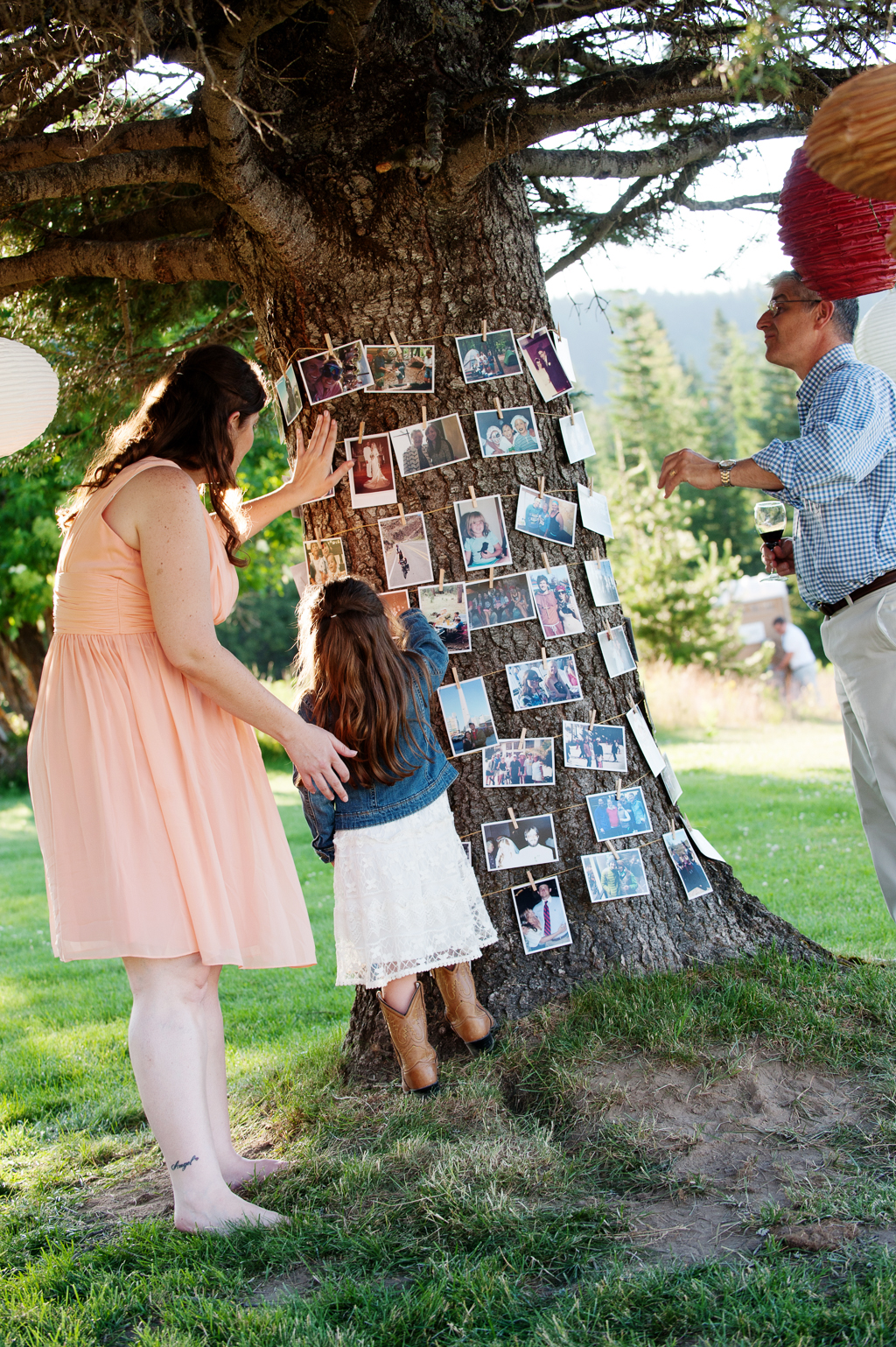 a mom and daughter look at photographs that are wrapped around a large tree