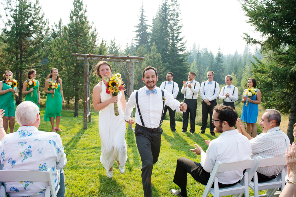 a bride and groom skip excitedly away from their wedding ceremony at mount hood