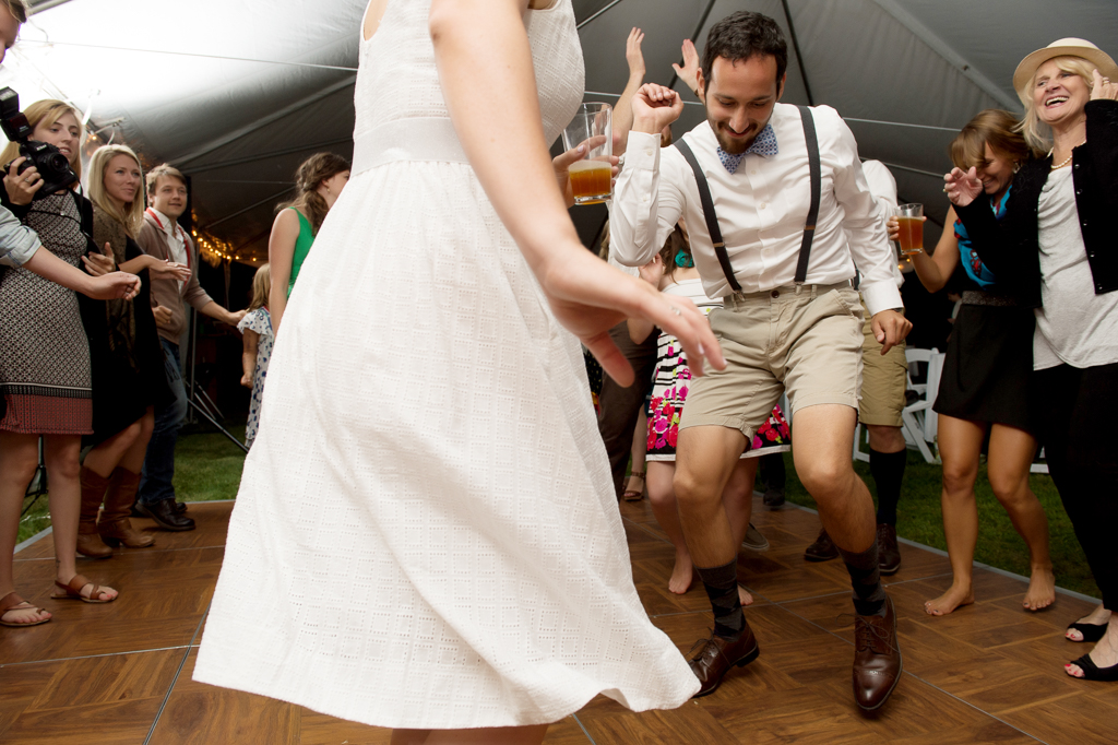 a groom dressed in lederhosen dances at his wedding reception
