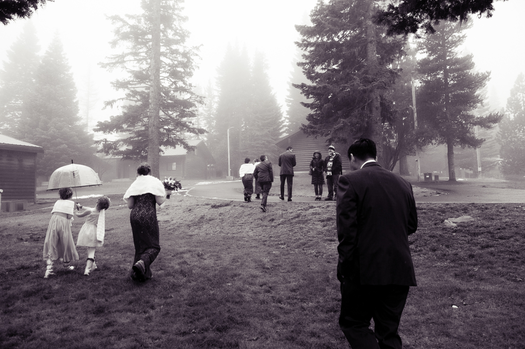 wedding guests walk through a foggy yard
